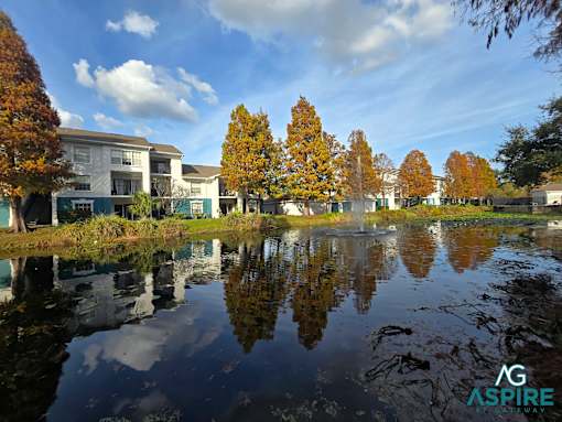 A serene lake in front of a building surrounded by trees.