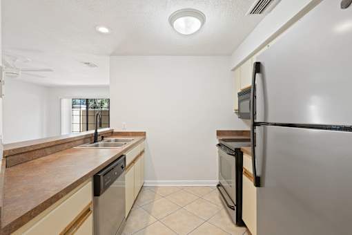 A kitchen with a black fridge and a black dishwasher.