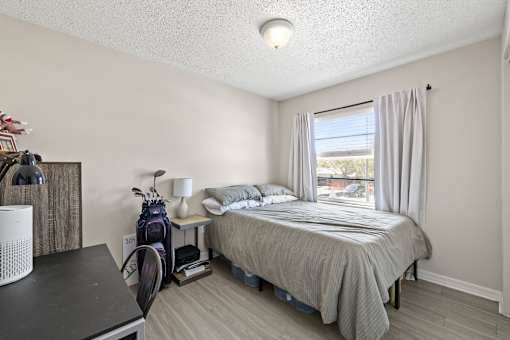 A bedroom with a bed, nightstand, and window.