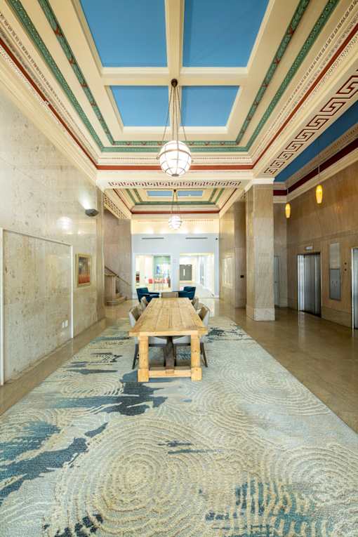 A long hallway with a blue carpet and a wooden table.