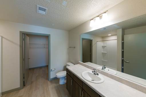 A bathroom with a toilet, sink, and mirror.