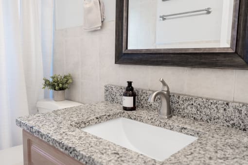 a bathroom sink with a mirror and toilet in a 555 waverly unit