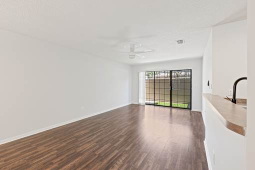 A room with a ceiling fan and a window with bars.