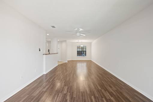 A long empty room with wooden floors and white walls.