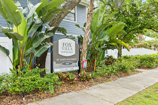 A sign for Fox Villa Townhomes in BC Tampa is displayed in front of a house.