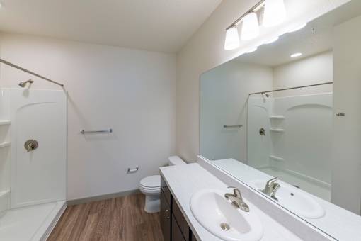 A white bathroom with a toilet, sink, and shower.