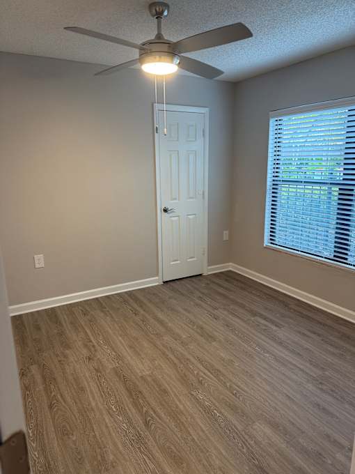 A room with a ceiling fan and a door.