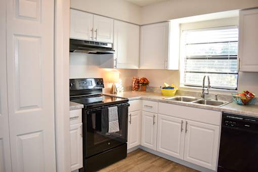 A kitchen with black appliances and white cabinets.
