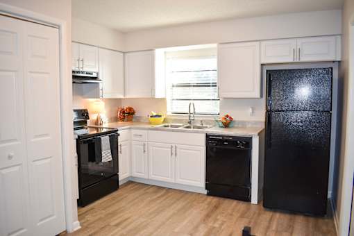 A kitchen with black appliances and white cabinets.