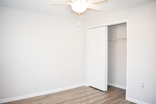 A white room with a ceiling fan and a white closet.