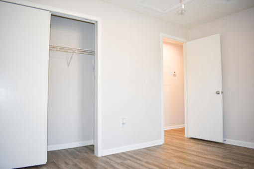A white door is open to a room with a wooden floor.
