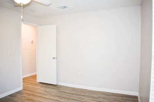 A room with a white door and wooden floor.