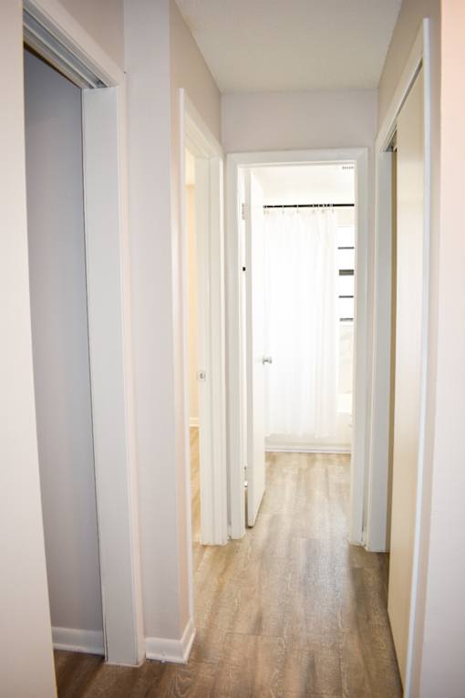 A long hallway with white walls and wood flooring.