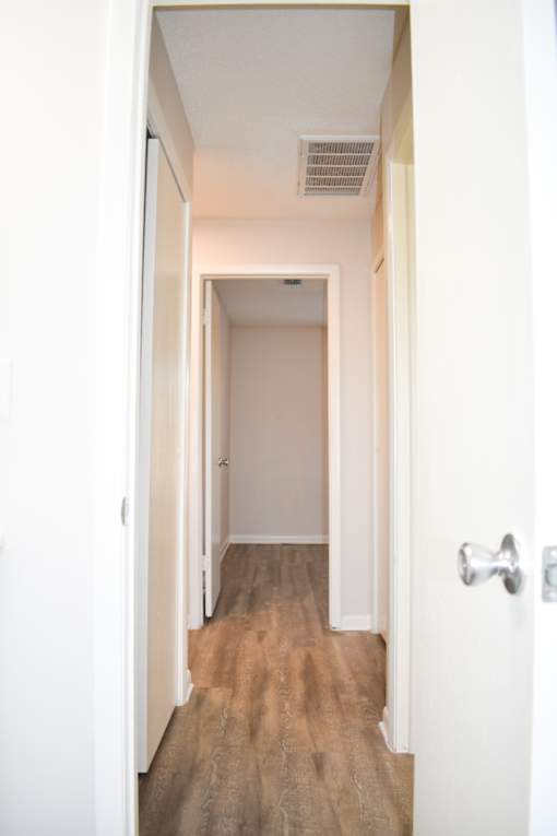 A hallway with a wooden floor and white walls.
