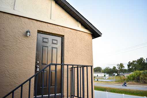 A brown house with a black door and a black railing.