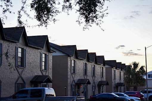 A row of houses with cars parked in front.