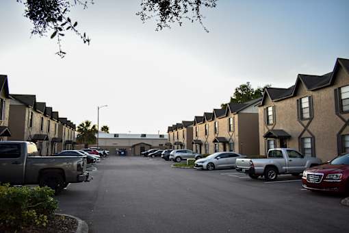 A parking lot with cars and trucks in front of apartment buildings.