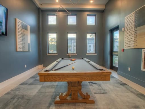 a pool table in a room with windows