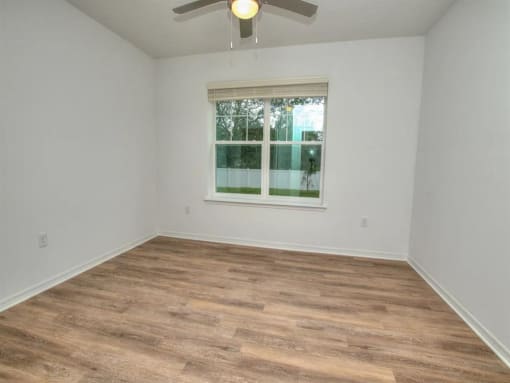 an empty room with a window and a ceiling fan