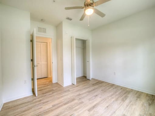 an empty living room with wood floors and a ceiling fan