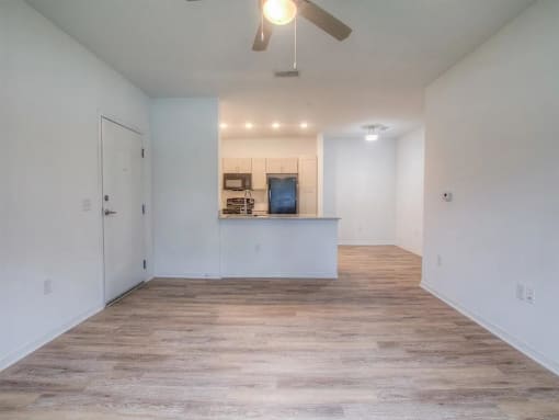 a living room and kitchen area with a ceiling fan
