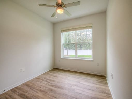 an empty room with a ceiling fan and a window