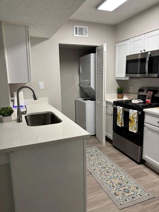 A kitchen with a white countertop and a black dishwasher.