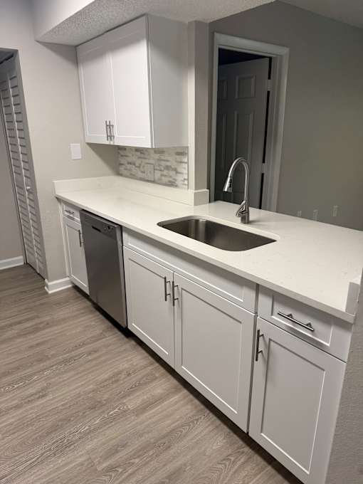 A kitchen with white cabinets and a sink.