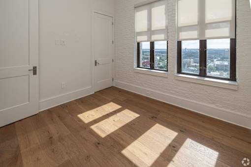 A room with wooden floors and a window overlooking a cityscape.