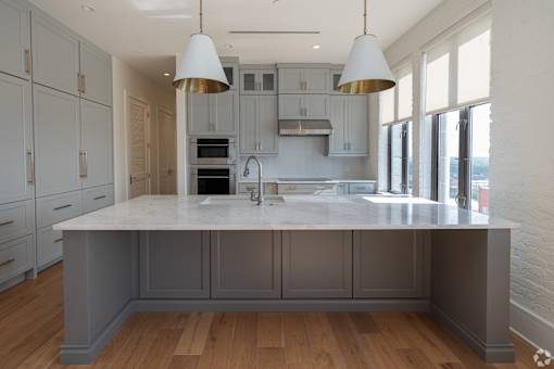 The Penthouse  A kitchen with a large island and pendant lights.