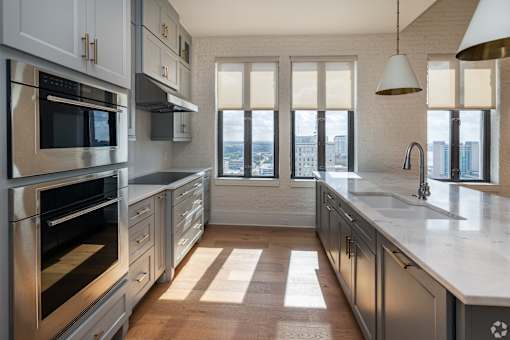 The Penthouse  A modern kitchen with stainless steel appliances and a view of the city.