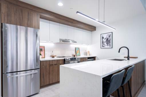 A modern kitchen with a stainless steel refrigerator and a white marble countertop.
