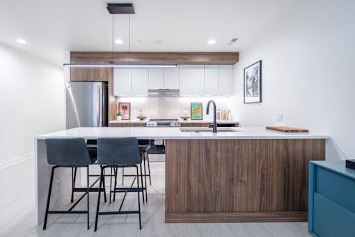 A modern kitchen with a wooden island and grey chairs.