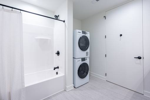 A white bathroom with a washer and dryer stacked on top of each other.