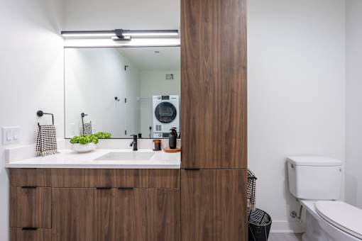 A bathroom with a wooden vanity and a white toilet.