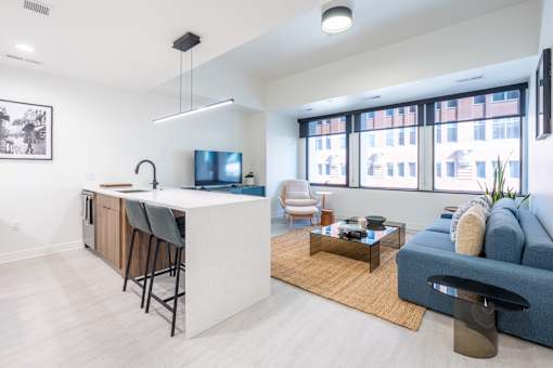 A modern kitchen with a bar and a blue couch.