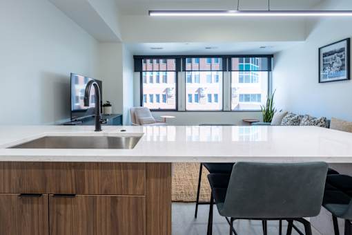A modern kitchen with a white countertop and a large window.