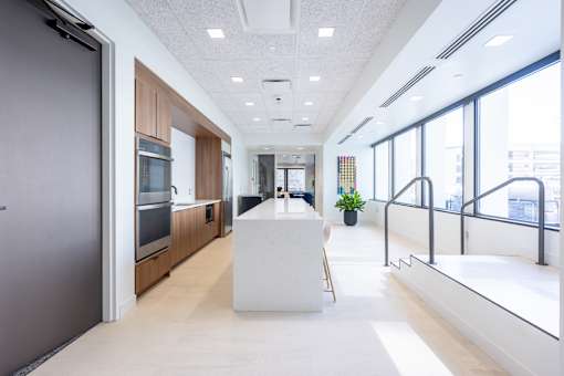 A modern kitchen with a white table and a plant in the background.