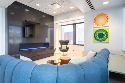 A blue couch in a room with a television and a chair.