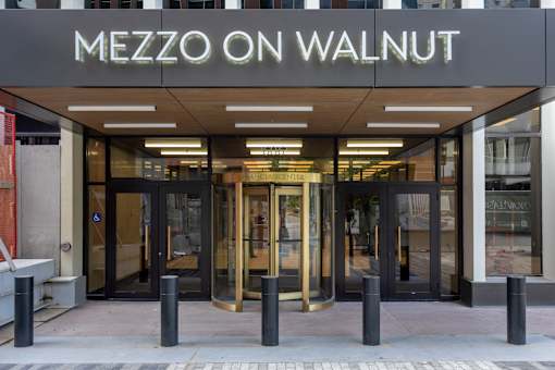 The entrance to a Mezzo on Walnut restaurant with a glass door and a black pole.