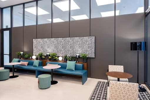 A modern office lounge with blue seating and a large abstract painting on the wall.