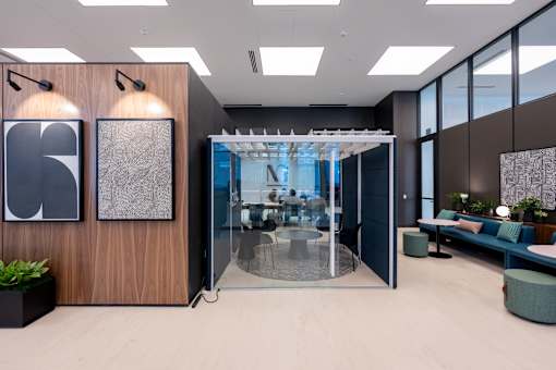 A modern office space with a glass wall and a wooden panelled wall.