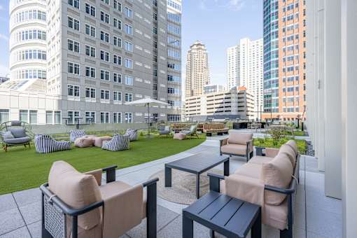 A patio with chairs and tables overlooks a cityscape.