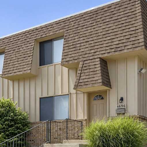 A house with a brown roof and a white wall with a number 4696 on it.
