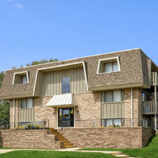 A modern house with a brown brick facade and a grey roof.