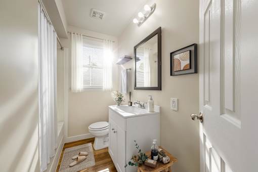 A white bathroom with a toilet, sink, and mirror.