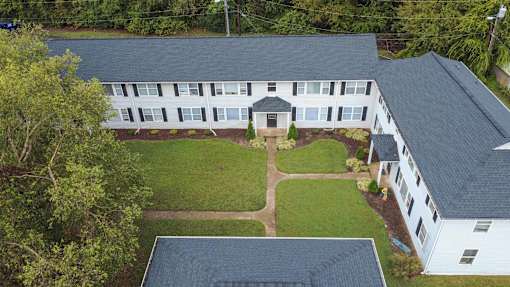 A white building with a black roof and a green lawn in front.