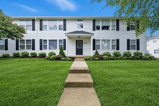 A white building with a black front door and steps leading to it.