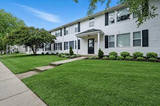 A white two-story apartment building with a black front door and windows.