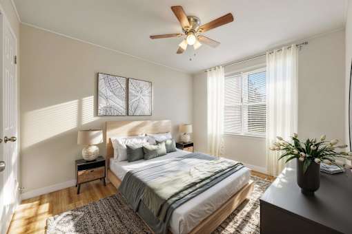 A bedroom with a bed, nightstand, and a ceiling fan.